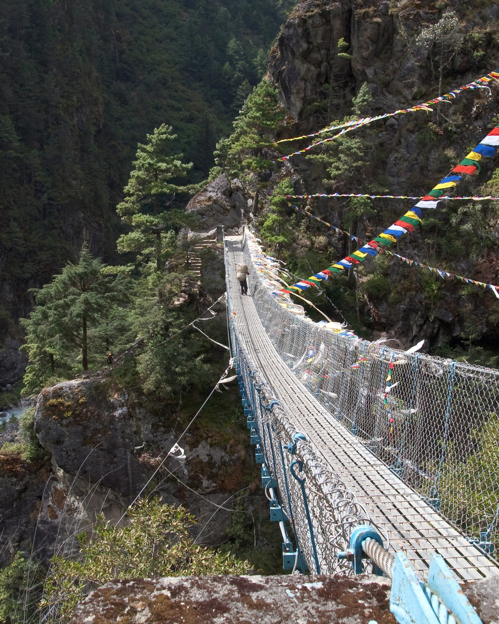 A steel suspension bridge strung with prayer flags crossing high above the Dudh Kosi gorge.