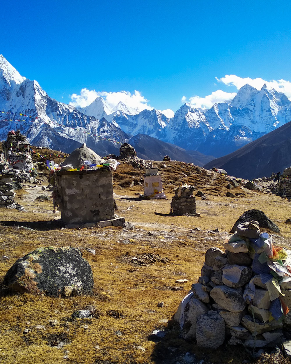 Stone memorial cairns hung with prayer flags on the Thukla Pass, peaks in the distance.