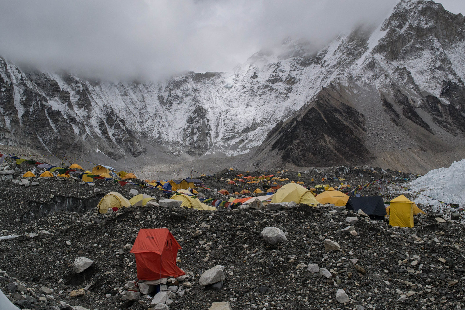 Expedition tents pitched on the moraine of the Khumbu glacier at Everest Base Camp beneath storm cloud.