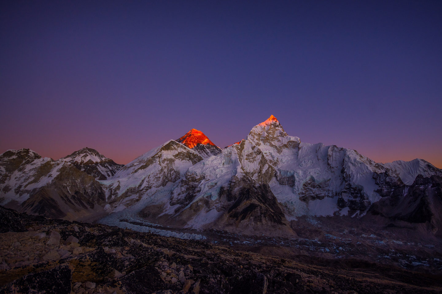 Alpenglow on Everest and Nuptse at dusk, the Khumbu valley falling away in shadow beneath a violet sky.